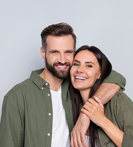 A man and woman are embracing each other, smiling warmly. They appear to be a couple celebrating an occasion together.