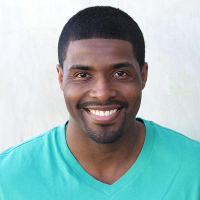 A man and woman are sitting closely together, smiling at each other, with the man s arm around the woman, suggesting a close relationship between them.