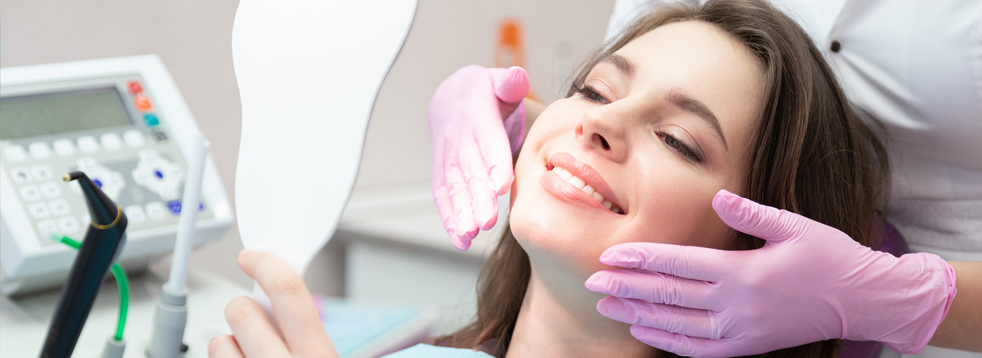 A woman receiving dental care with a hygienist using an ultrasonic scaler on her teeth.