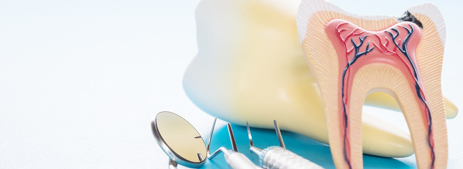 The image shows a close-up of a toothbrush with a toothpaste tube on top, placed next to an illustration of a mouth model with teeth and gums, set against a plain background that suggests a dental care theme.